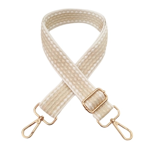 Detail of wide woven bag strap with gradient beige pattern and gold metal hooks