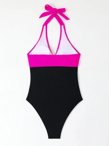 Detail view of pink and black halter neck swimsuit with a large bow tie decoration