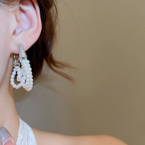 Detailed view of layered pearl tassel earrings with zircon studs on female model