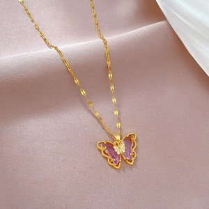 Elegant gold butterfly necklace with purple gemstone on a soft satin background