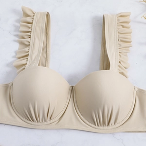 Detail of beige bikini top with ruffled straps, underwire cups, and pleated texture