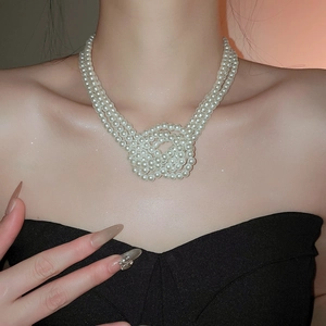 Detail of a three-layer French pearl necklace with a complex woven knot design