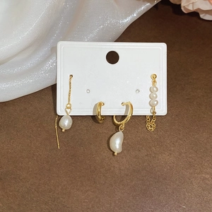 Detailed set of golden freshwater pearl drop earrings and minimalist hoops on display