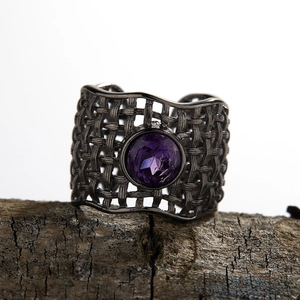 Macro detail of purple amethyst ring with gun black woven texture on vintage bark