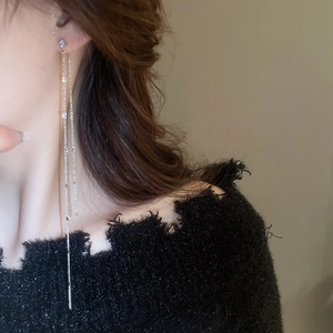 Close-up of long silver tassel earrings with cubic zirconia on a female model