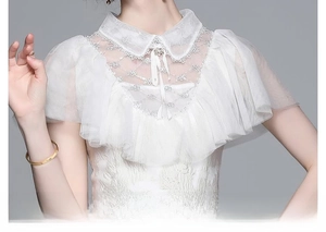 Détail du col en dentelle blanche élégante avec bouton perle et broderie sur la robe