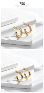 Detail showing gold-plated C-shaped earrings with clear and colorful zircon crystals