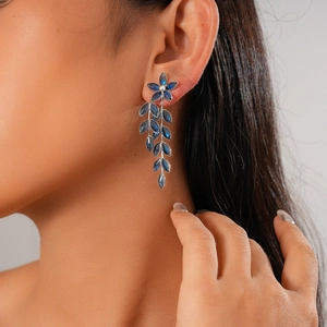 Detail of silver drop earrings with blue floral crystals and leaf tassels on a model