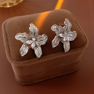 Nahaufnahme glitzernder Blumenohrstecker mit Zirkonia auf einer braunen Samtbox