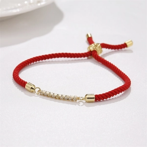 Detail view of red braided cord bracelet with gold bar and clear cubic zirconia stones