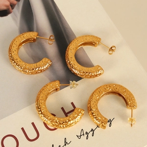 Golden C-shaped textured earrings with hammered metal finish on a fashion magazine
