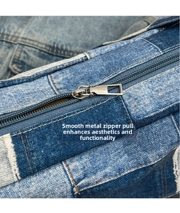 Détail de la fermeture éclair en métal argenté sur un sac en denim bleu avec surpiqûres
