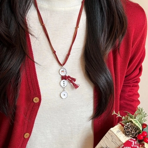 Détail du collier long bonhomme de neige avec pendentifs blancs et pompon rouge élégant