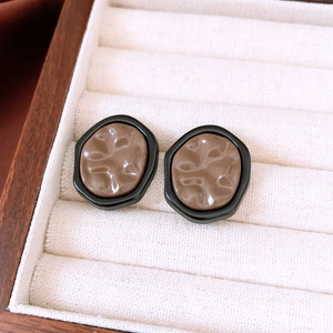 Detail view of French vintage irregular earrings with coffee resin and black frames