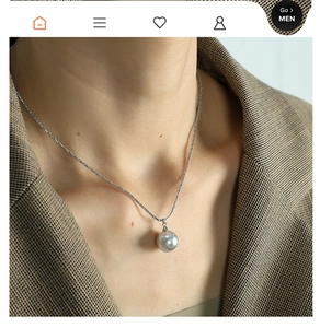 Detailed close-up of a lustrous pearl pendant necklace worn on a woman neck in French style
