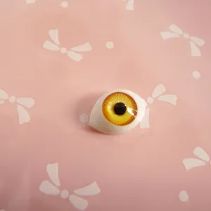 Macro detail of amber acrylic boat-shaped doll eye with realistic iris texture