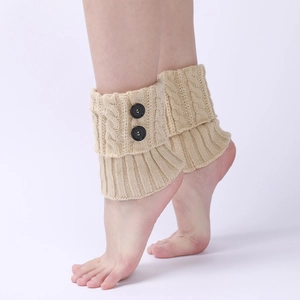 Detail of beige cable-knit leg warmers with decorative black buttons and ribbed cuffs