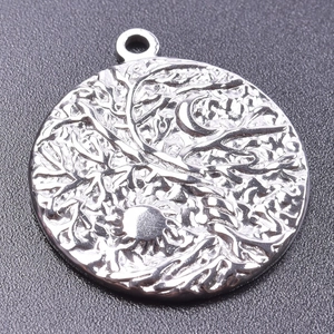 Macro detail of silver Tree of Life pendant with celestial sun and moon relief symbols