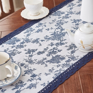 Linen table runner with blue floral patterns and navy lace edges on wooden desk
