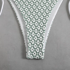 Detail of white crochet bikini bottom with dark green lining and side tie strings