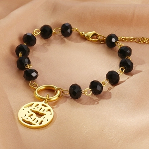 Detail of beaded bracelet with black crystals and gold mama pendant on satin