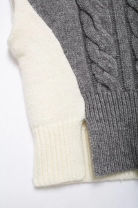 Close-up of cable knit patterns and side slit on the grey and beige knit vest