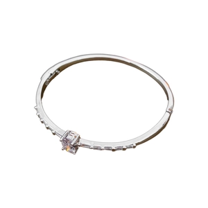 Elegant silver metal oval bangle featuring a round central zircon and baguette accents