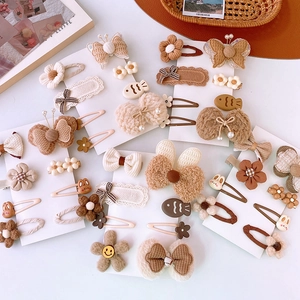 Dettaglio di fiocchi di peluche beige e fermagli per capelli con fiori su cartoncino