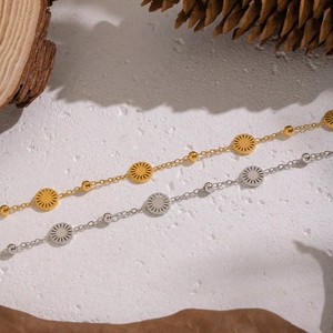 Minimalist 18K gold and silver stainless steel sun disc bracelets on a rustic stone background