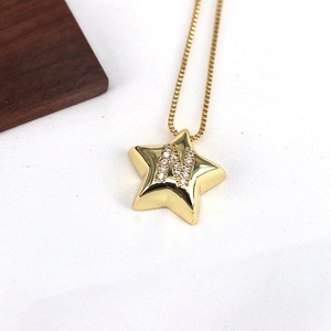 Close-up of gold star pendant with letter N and micro-inlaid zircon on a box chain