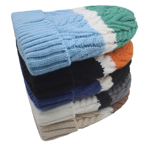 Close-up of cable knit textures and ribbed edges on stacked colorful winter beanies