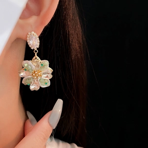 Détail macro de boucles d'oreilles fleurs en cristal aux pétales vert clair et doré