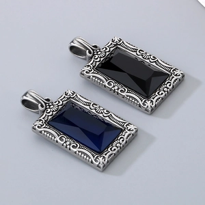 Gros plan de pendentifs vintage en acier gravé avec pierres précieuses carrées noires et bleues