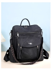 Detail of black PU backpack featuring tassel charm and geometric pattern wide shoulder strap