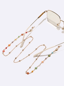 Détail de la chaîne à lunettes dorée avec fleurs en émail coloré et boucles en silicone