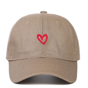 Detailed embroidery of a red heart on a beige cotton canvas baseball cap surface