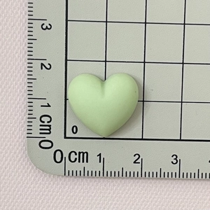 Detail view of a 2.5cm light green macaron resin heart charm on a scale measurement mat