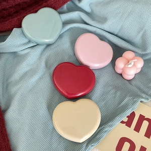 Detailed view of candy-colored heart-shaped contact lens cases in four pastel shades