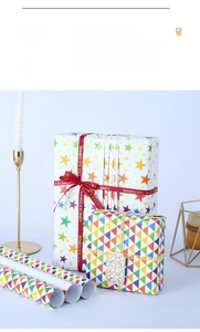 Detail of colorful star, triangle, and polka dot gift wrapping paper with red silk ribbons