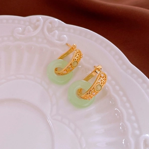 Close-up of gold-plated hoop earrings with green jade donuts and sparkling cubic zirconia