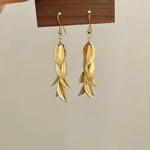 Détail de boucles d'oreilles feuilles dorées superposées avec sequins et crochets polis