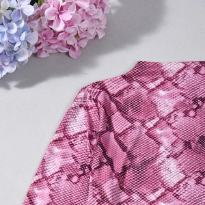 Gros plan sur le tissu à imprimé serpent rose montrant la texture et les motifs violets