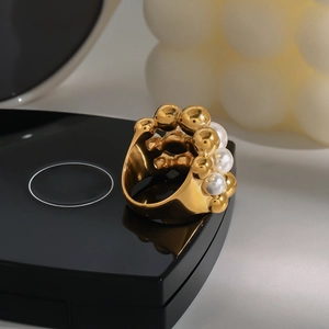 Macro detail of a gold stainless steel ring featuring circular white pearl arrangement