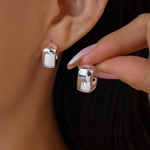 Macro detail of thick silver U-shaped hoop earrings with a high-polished mirror finish