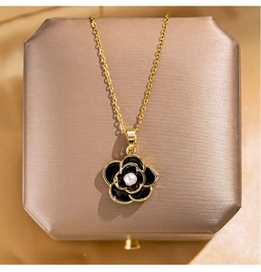 Close-up of gold camellia necklace with black enamel petals and a central pearl