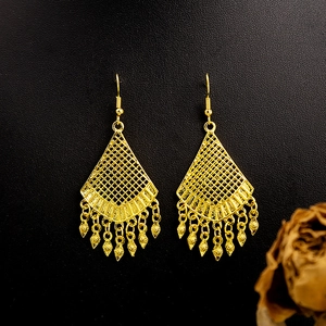 Detailed view of bohemian gold hollow mesh earrings with leaf tassel charms on black texture