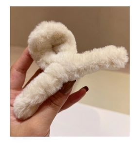 Détail de la pince à cheveux en peluche crème avec un design croisé pour l'automne-hiver