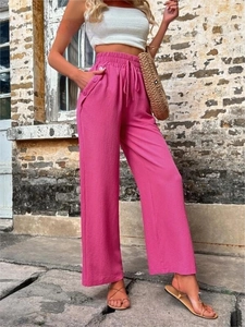 Détail du pantalon large rose avec cordon à la taille et boutons décoratifs sur le côté
