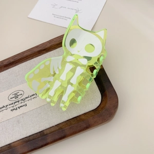 Macro view of neon yellow translucent acrylic cat skull hair claw clip on wooden tray
