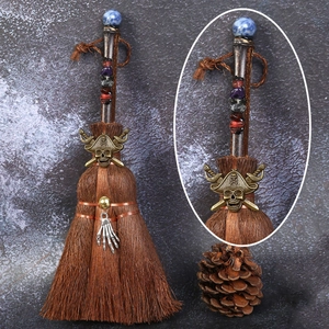 Detail of crystal witch broom with blue stone, skull charms and brass pirate emblem